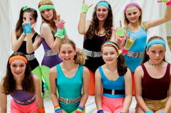 Eight girls in brightly coloured leotards and 80s headbands