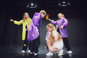 Children in raincoats performing on stage